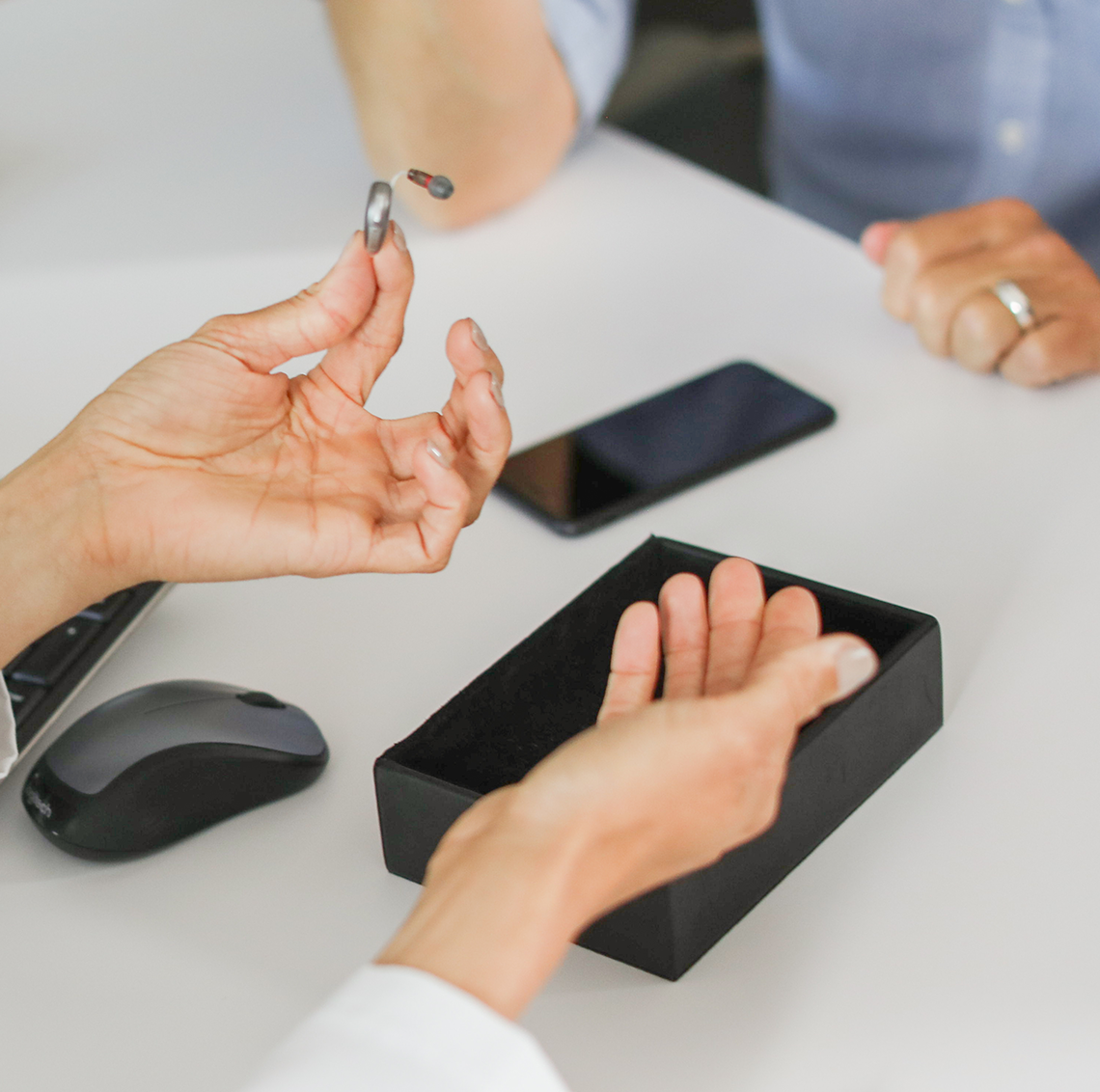 Hearing professional demoing hearing aids to patient