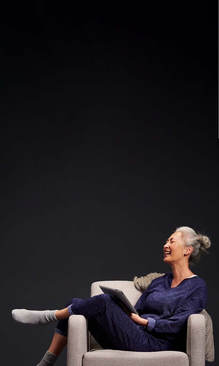 Smiling woman in a chair looking at a tablet