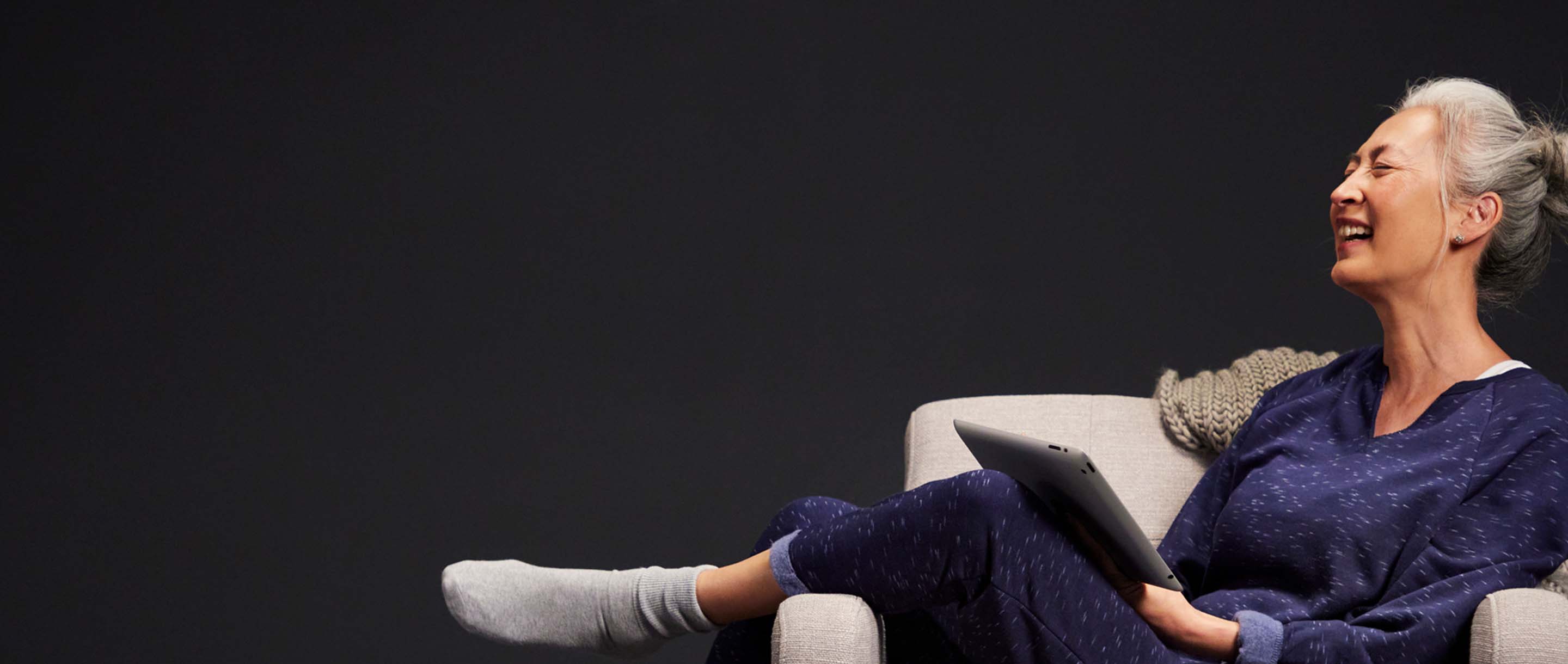 Smiling woman in a chair looking at a tablet