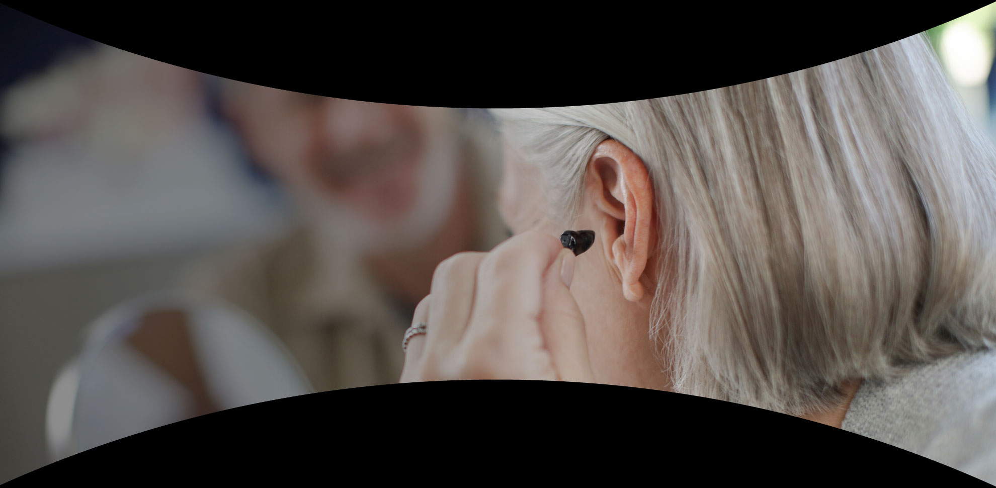 signature series woman placing hearing aid in ear